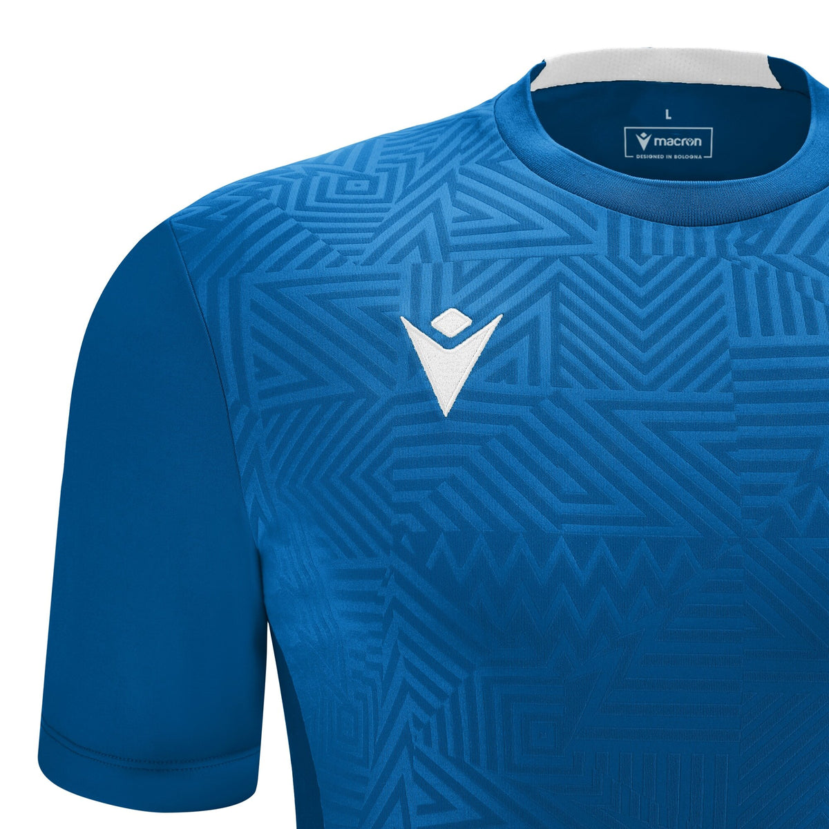 Close-up of the Macron logo and textured pattern on the blue Macron referee training top
