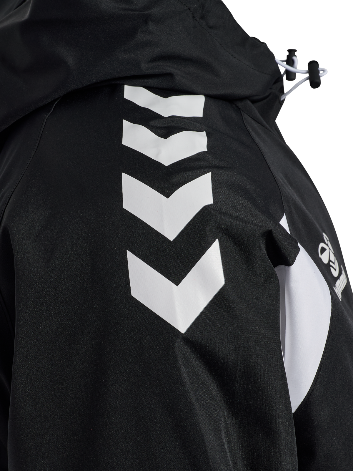 Close-up of the white chevrons on the sleeve of the black Hummel referee rain jacket